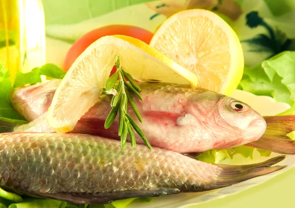 stock image Fresh fish, crucian with a lemon and an onions, salad with olive oil