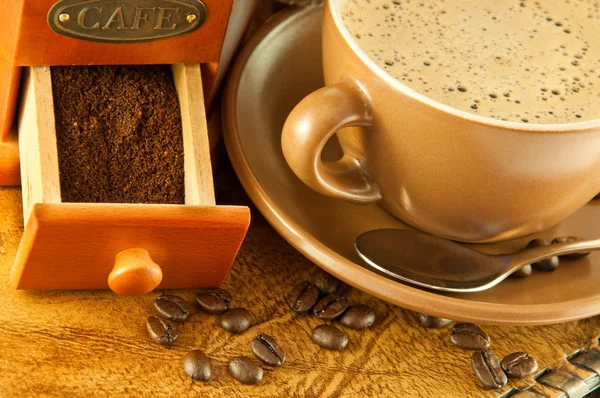 Moulin à café dans un style rétro, une tasse de café sur fond de grange — Photo