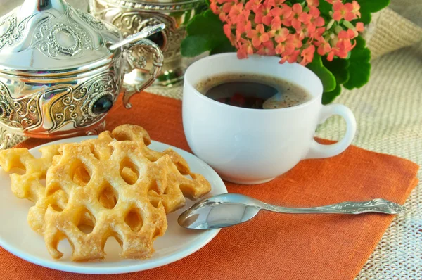 Biscuits et café sur une table aux fleurs naturelles, table argentée — Photo