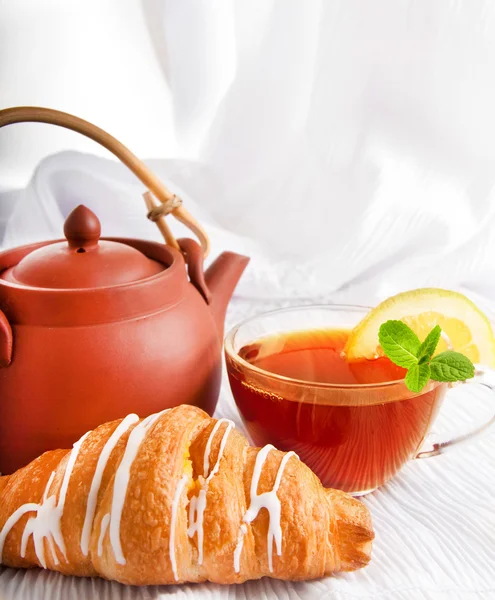 Cup of fragrant tea flowing from a ceramic teapot — Stock Photo, Image