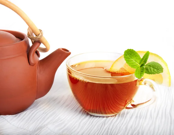 Cup of fragrant tea flowing from a ceramic teapot — Stock Photo, Image