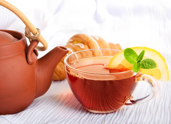 Xícara de chá perfumado que flui de um bule de cerâmica — Fotografia de Stock