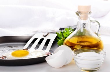 Fried eggs on a frying pan with olive oil and an egg shell