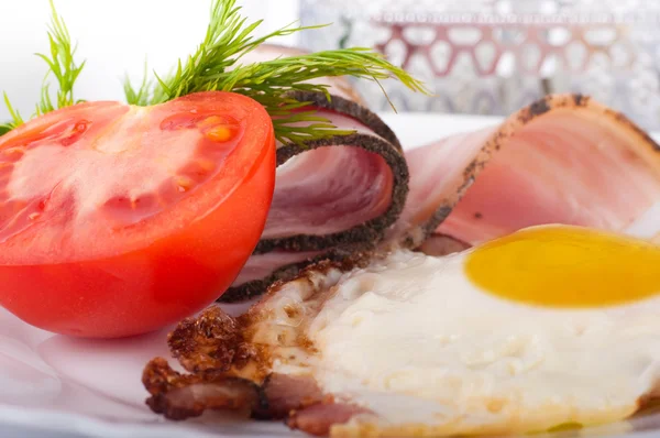 Fried eggs with bacon and tomatoes, a nourishing breakfast — Stock Photo, Image