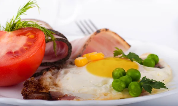 Gebakken eieren met spek en tomaten, een erwten en maïs, een voedzaam ontbijt — Stockfoto
