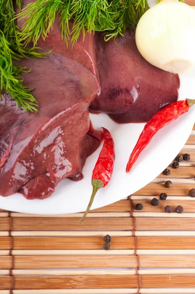 stock image Pork liver with pepper and an onion on a bamboo board