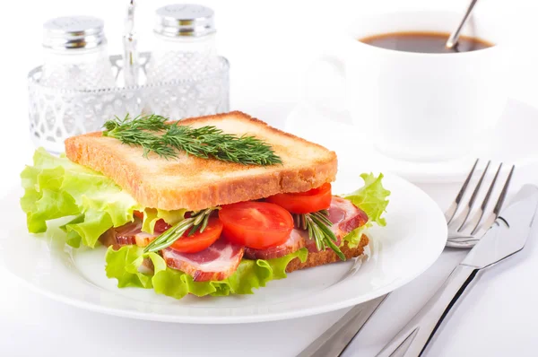 Sandwich from smoked meat and tomatoes, a cup of coffee — Stock Photo, Image