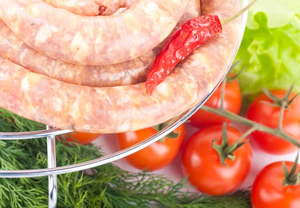 Sausage from pork and beef on a grill, tomatoes, salad and spices — Stock Photo, Image