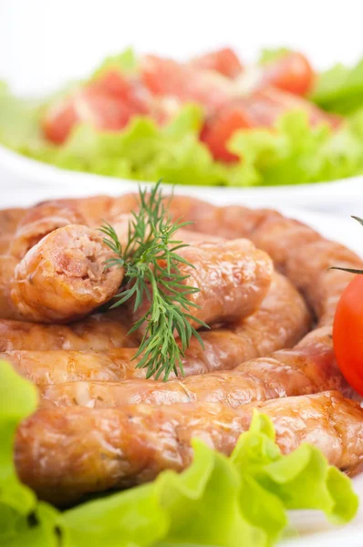 Сосиски из свинины и говядины с помидорами и специями, овощной салат — стоковое фото