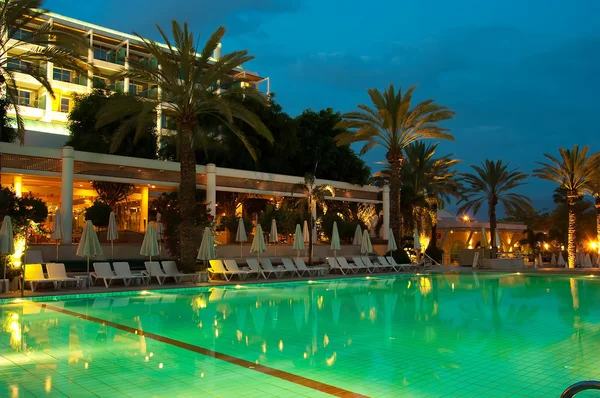 W nocy basen na tle drzew palmowych i Hotele — Zdjęcie stockowe