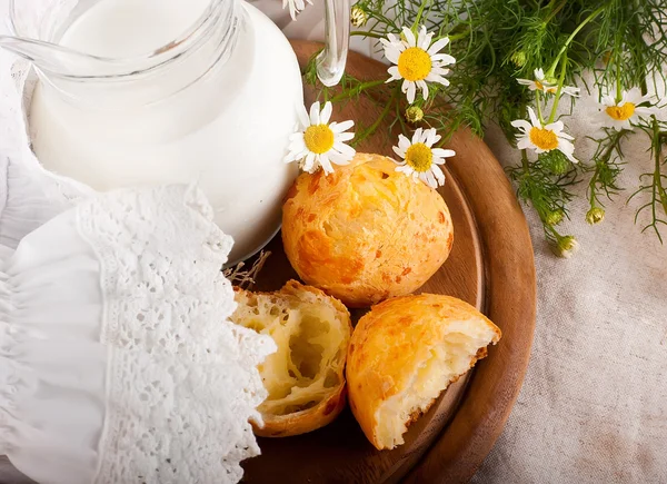 Caraffa con latte, pane e fiori selvatici su sfondo bianco — Foto Stock