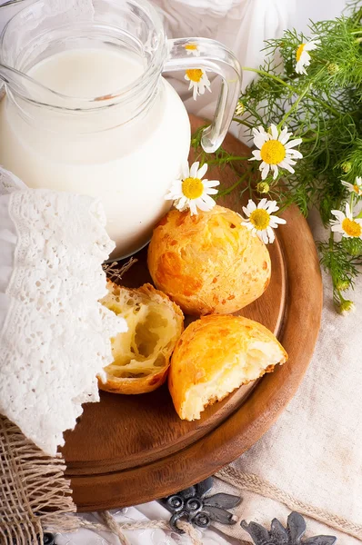 Кувшин с молоком, хлебом и дикими цветами на белом фоне — стоковое фото