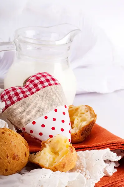 Krug mit Milch, Brot und rotem Herz auf weißem Hintergrund — Stockfoto