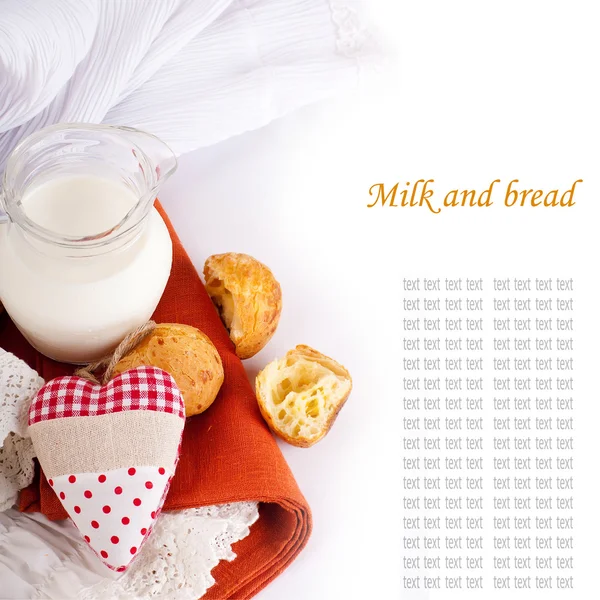 Jarro com leite, pão e coração vermelho em um fundo branco — Fotografia de Stock