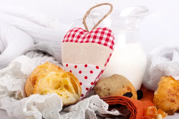 Caraffa con latte, pane e cuore rosso su sfondo bianco — Foto Stock