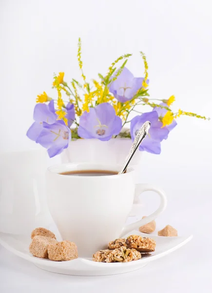 Uma xícara de café com pastelaria e bluebell azul está em um vaso — Fotografia de Stock