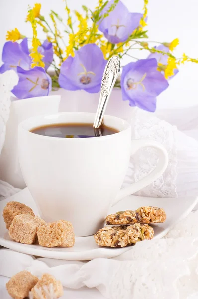 A cup of coffee with pastry and blue bluebell is in a vase — Stock Photo, Image