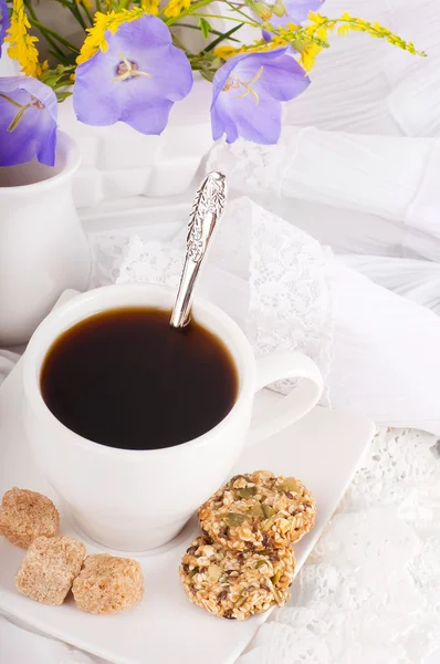 A cup of coffee with pastry and blue bluebell is in a vase — Stock Photo, Image