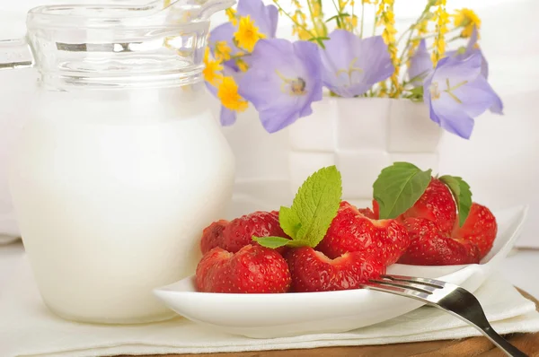 Jahody s mátou a džbán mléka na bílý ubrousek — Stock fotografie