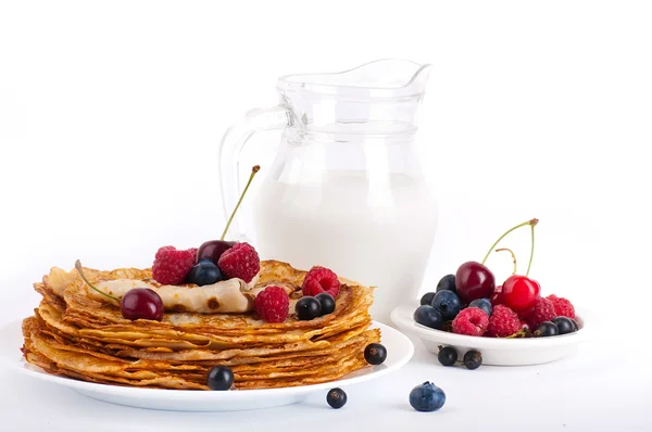 Pancakes with berries and jug of milk — Stock Photo, Image