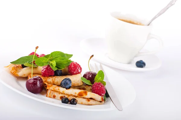 Млинці з ягодами, м'ятою та чашкою кави на білому фоні — стокове фото