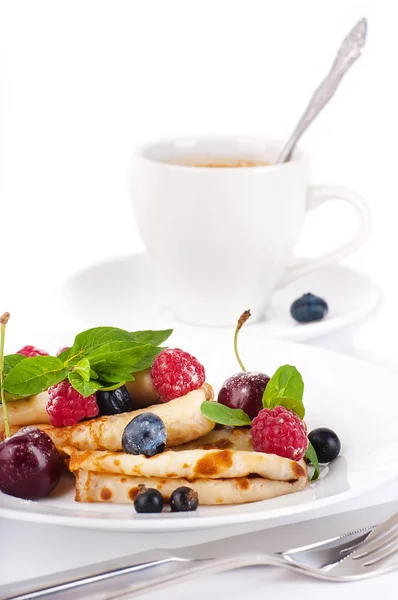 Pancakes with berries and mint and cup of coffee on a white background — Stock Photo, Image
