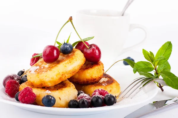 Cheese pancakes with forest berries and cup of coffee — Stock Photo, Image