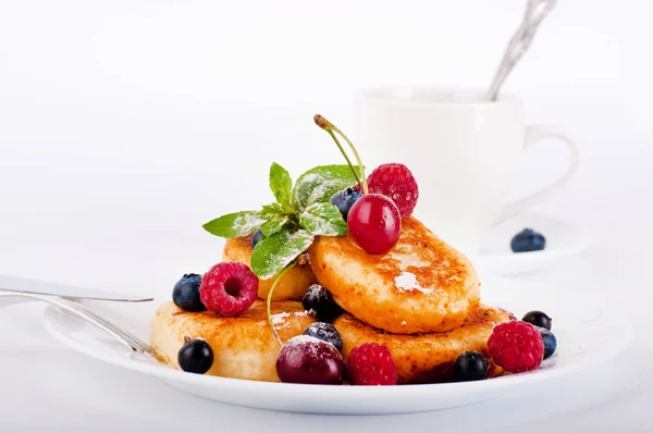 Cheese pancakes with forest berries and cup of coffee — Stock Photo, Image