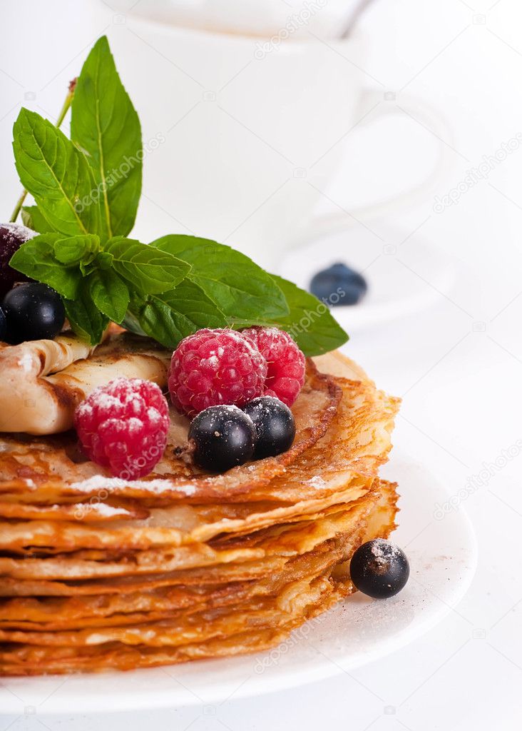 Pancakes with berries and mint on a white background