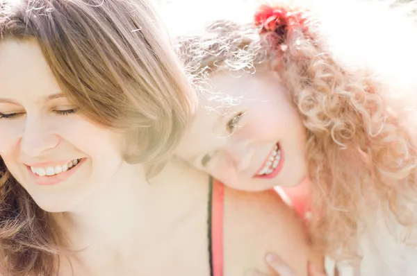Glückliche kleine Tochter umarmt ihre junge Mutter — Stockfoto
