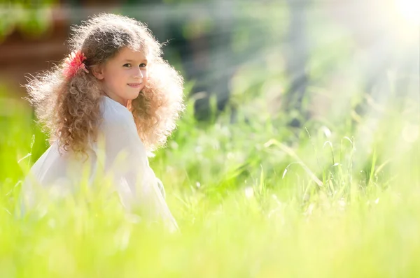 Красивая маленькая девочка улыбается и ходит в поле — стоковое фото