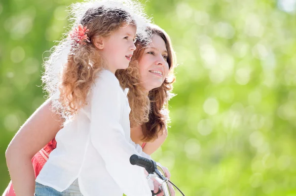 Jovem mãe e sua filha na bicicleta — Fotografia de Stock