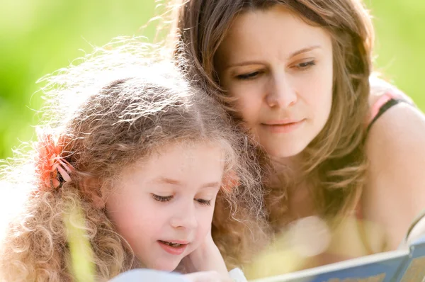 Bella bambina leggere libro con ger madre — Foto Stock