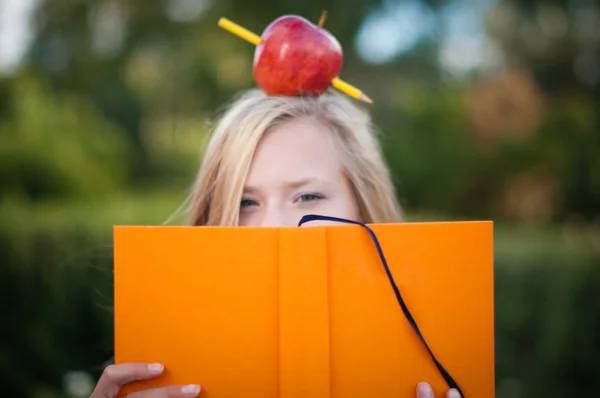 Junge Studentin mit Apfel auf dem Kopf — Stockfoto