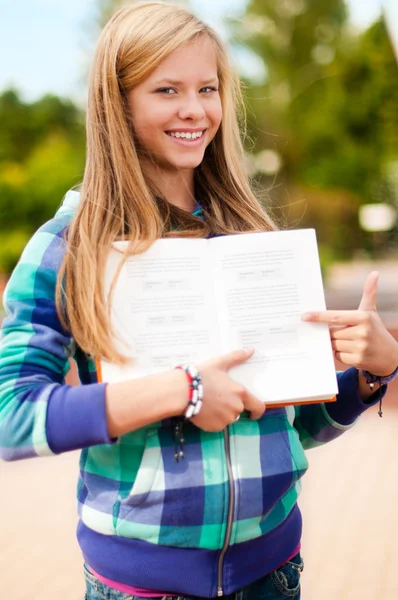 Fiatal diák lány mutatja valami könyv — Stock Fotó