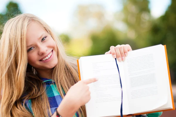 Mladý student dívka ukazuje něco v knize — Stock fotografie