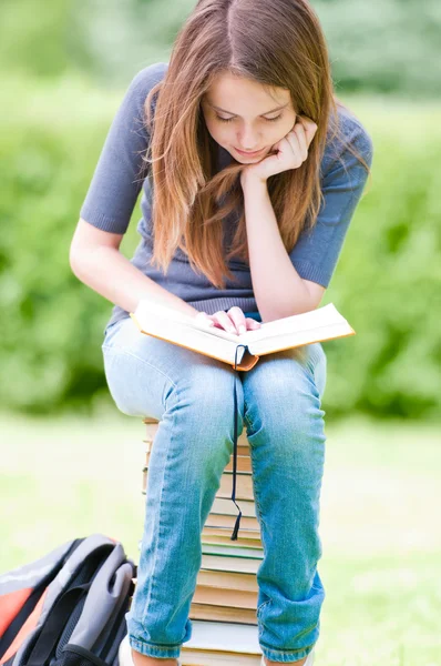 Boldog diák lány halom könyvet ül — Stock Fotó