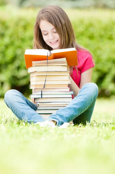 Menina estudante feliz sentado na grama e leitura — Fotografia de Stock
