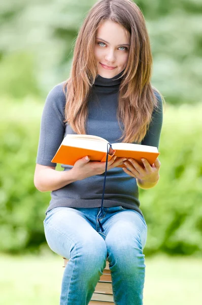 Heureuse étudiante assise sur une pile de livres — Photo