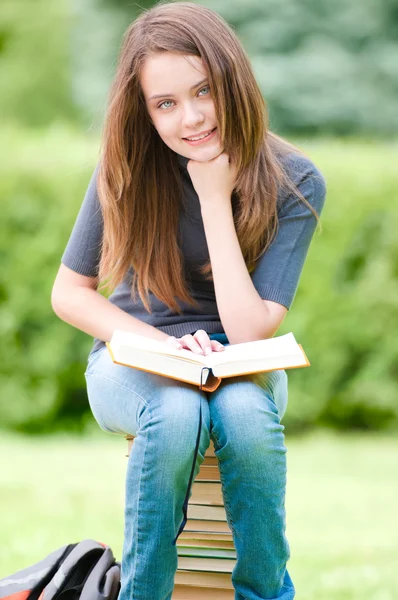 本の山に座っている幸せな学生の女の子 — ストック写真