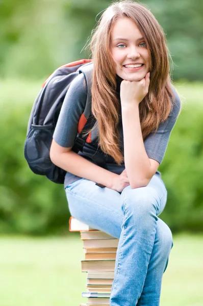 Menina estudante feliz sentado em livros — Fotografia de Stock