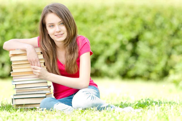 Yığın kitap üzerinde oturan mutlu öğrenci kız — Stok fotoğraf