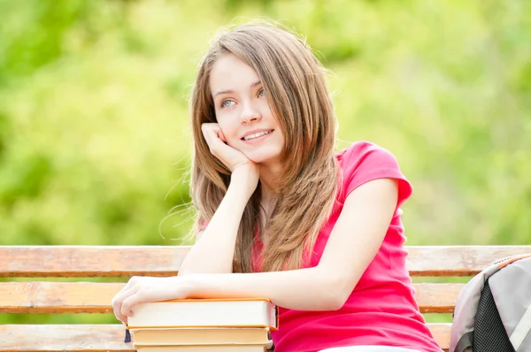 Menina estudante feliz sentado no banco com livros e sonhando — Fotografia de Stock