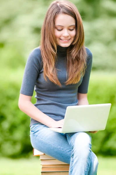Счастливая студентка работает на ноутбуке — стоковое фото