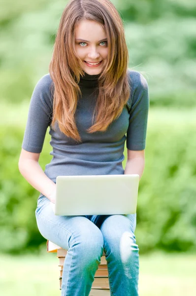 Счастливая студентка работает на ноутбуке — стоковое фото