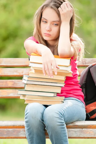 悲伤的年轻学生女孩坐在长椅上与书 — 图库照片