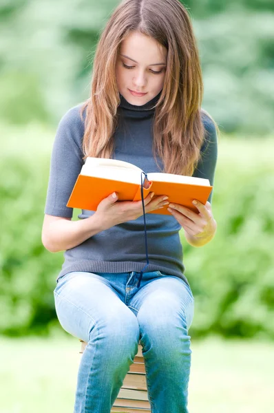 Serious student girl sitting on pile of books — Stock Photo, Image