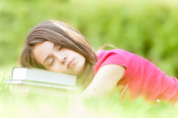 Jovem estudante menina dormindo na pilha de livros — Fotografia de Stock