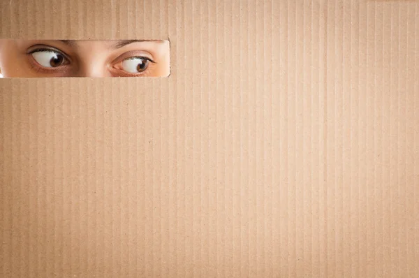Woman looking through the hole in cardboard — Stock Photo, Image