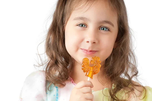 Маленькая девочка улыбается и ест конфеты — стоковое фото